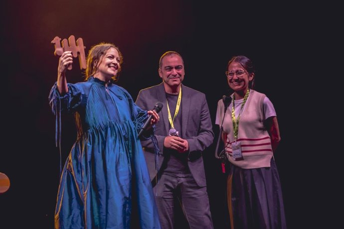 Natalia Lafourcade recoge el Premio Pirineos Sur a la Diversidad Cultural 2025 de manos del diputado de cultura de la Diputación Provincial de Huesca, Carlos Sampériz, y de la directora del festival, Amalia Ortiz.
