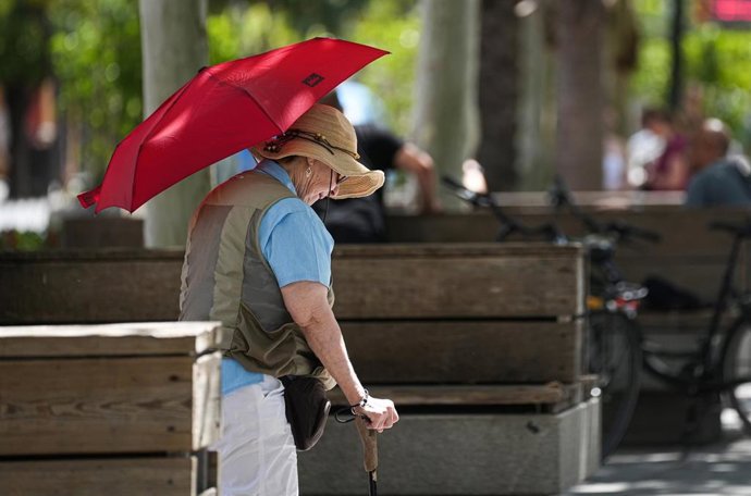 Archivo - Una mujer con sombrero y sombrilla paseando por puerta de Jerez. A 05 de julio de 2024, en Sevilla (Andalucía, España). Andalucía afronta este martes la primera jornada de la segunda ola que se extenderá hasta el jueves 25 de julio, tras la fina