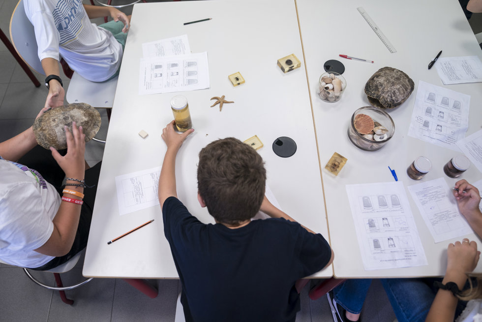 Un niño en una mesa de un aula con distinto material escolar.