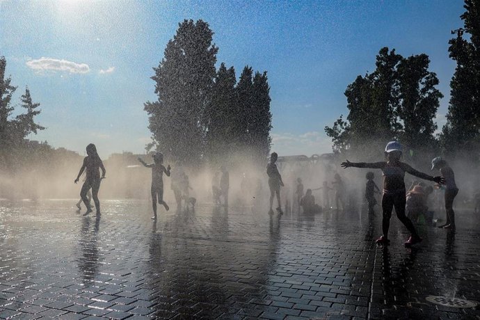 Archivo - Varios niños se refrescan en una fuente en Madrid
