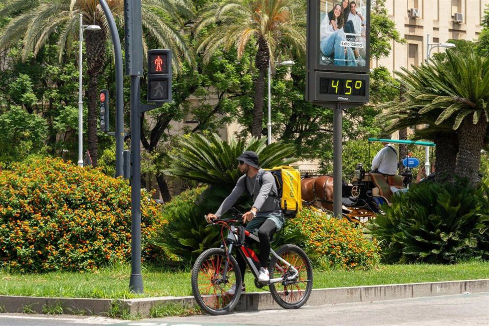 Archivo - Un termómetro marca 45 grados a las 14:00 de la tarde junto a un trabajador de Glovo en bicicleta, a 19 de julio de 2024, en Sevilla, Andalucía (España).