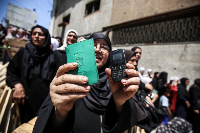 July 12, 2025, Gaza City, Gaza Strip, Palestinian Territory: Palestinians carry away bags of flour as others wait in front of a distribution point set up by the United Nations World Food Programme (WFP) in Gaza City on July 12, 2025