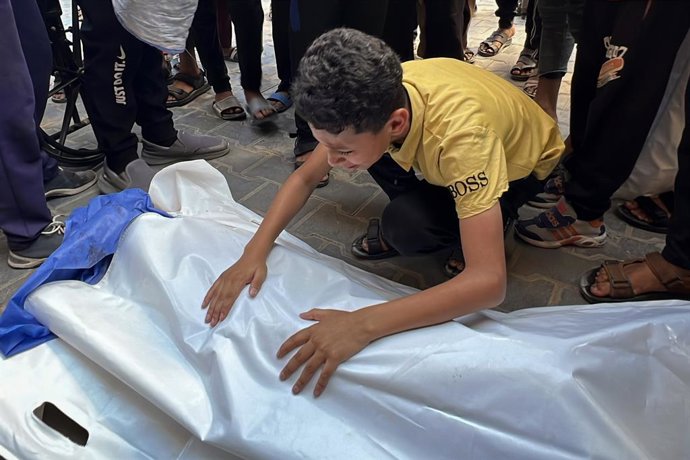 Un palestí junt amb els cadàvers de diversos morts per un atac d'Israel contra un punt de recollida d'aigua en el campament de Nuseirat, a la Franja de Gaza (arxiu)