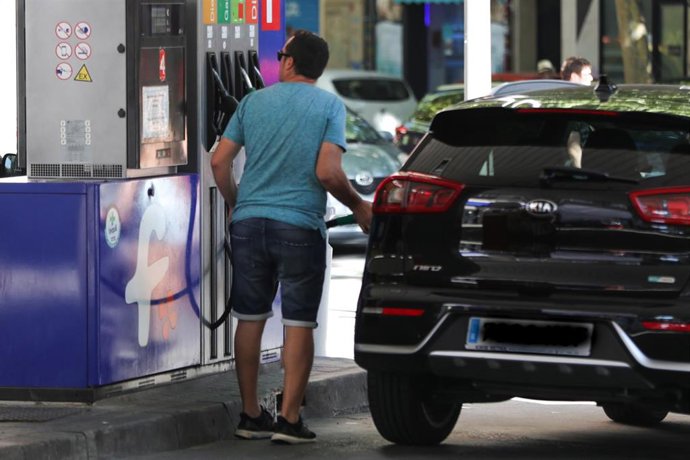 Archivo - Personas ponen gasolina en sus coches en una gasolinera de Madrid.