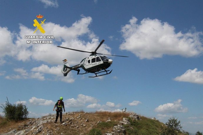 Imagen del helicóptero y uno de los agentes del Greim que rescataron a los senderistas en la Ruta Mielgo (León).
