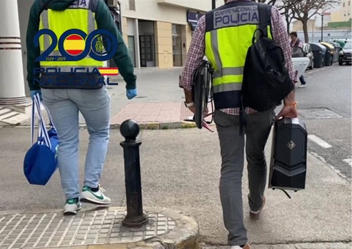 Dos agentes de la Policía Nacional con material intervenido a la red de pornografía infantil que operaba en la provincia de Cádiz.
