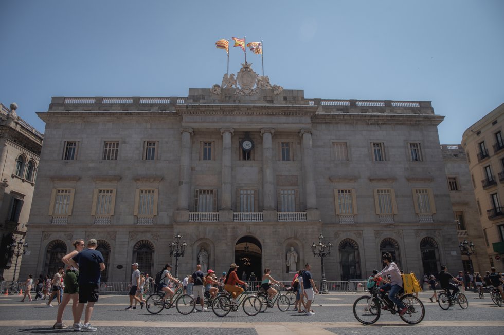 Varias personas caminan delante del edificio del Ayuntamiento de Barcelona