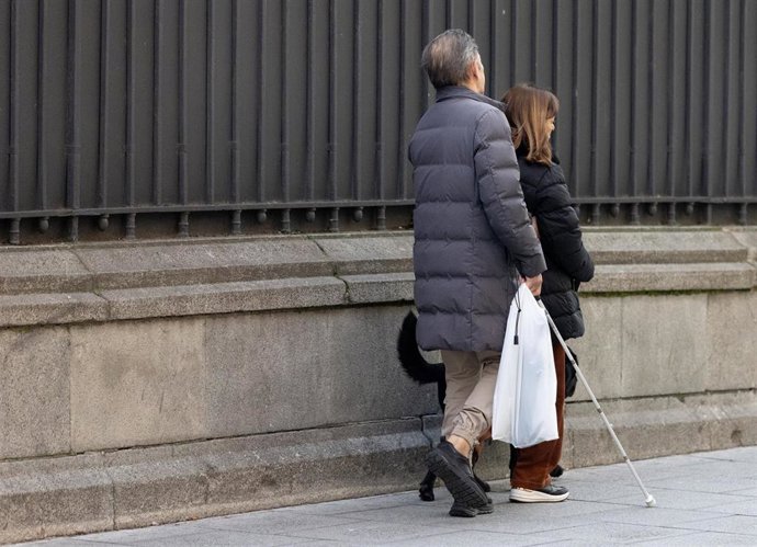 Archivo - Una persona con discapacidad visual camina acompañada por la calle, a 28 de enero de 2025, en Madrid (España).