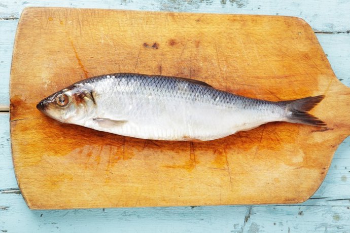Archivo - Herring on wooden chopping board on pale blue wooden table