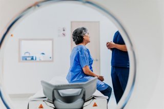 Archivo - Mujer hablando con el profesional sanitario al realizarse una resonancia magética.
