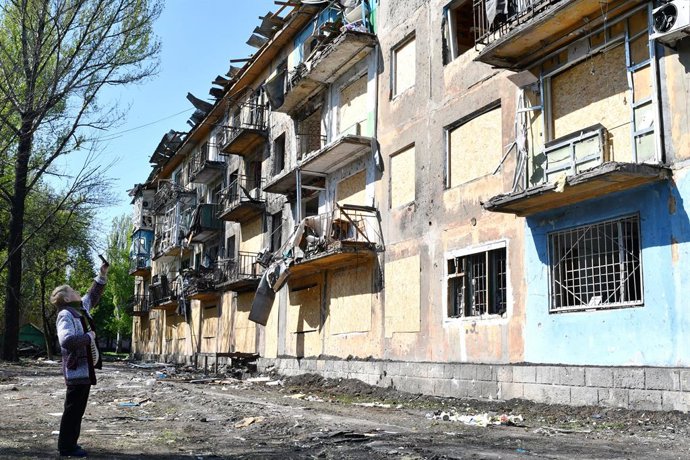 Archivo - Arquivo - 1º de maio de 2022, Dobropillya, Donetsk, Ucrânia: Uma mulher idosa tira uma foto com seu celular do prédio de apartamentos que foi danificado pelo bombardeio russo em Dobropillya. A Rússia foi forçada a deslocar forças "exauridas e dí