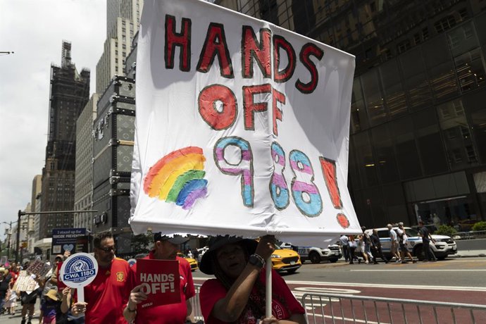 July 12, 2025, New York, New York, USA: Demonstrators protesting Trump administration plans to end 988 suicide prevention services for LGBTQ+ youth hold signs that read 'HANDS OFF 988!' 'CWA 1180' in a picket line outside of Trump Tower on Fifth Avenue in