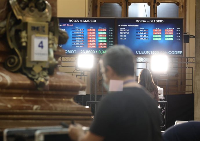 Archivo - Un hombre delante de dos paneles con valores del Ibex 35, en el Palacio de la Bolsa, a 4 de febrero de 2022, en Madrid (España). 