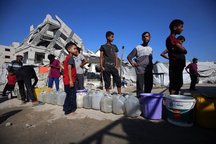 Palestinos intentan satisfacer sus necesidades diarias de agua llenando bidones de los camiones cisterna que llegan a la zona en la ciudad de Gaza.