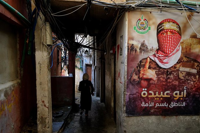 Archivo - 07 de agosto de 2024, Líbano, Beirute: Um refugiado palestino caminha em um beco estreito no campo de Beirute Burj al-Barjneh, decorado com um pôster de Abu Obeida, porta-voz das Brigadas Ezzedeen Al-Qassam do Hamas em Gaza. Foto: Marwan Naamani