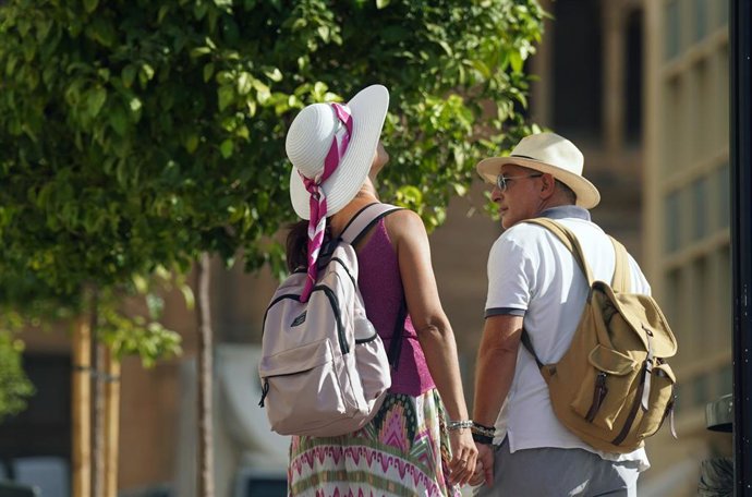 Dos personas con ropa veraniega y sombreros. A 18 de julio de 2025, en Málaga (Andalucía, España). 
