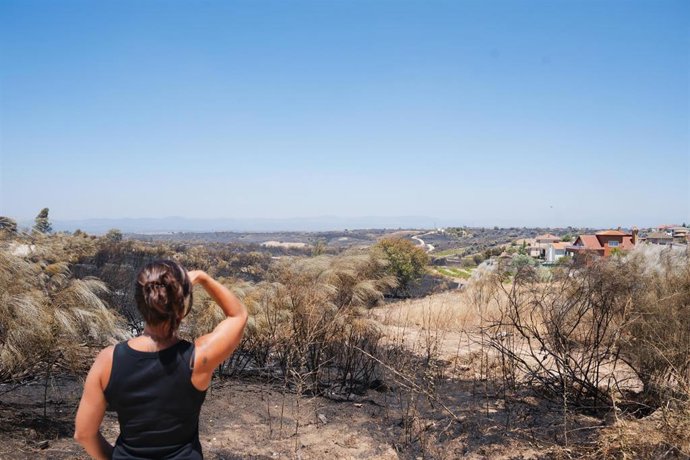 Una mujer observa el terreno afectado por el incendio que se originó ayer en Méntrida, desde la urbanización Calypo, a 18 de julio de 2025, en Casarrubios del Monte, Toledo, Castilla-La Mancha (España). 