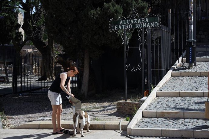 Una persona bebe usa una fuente en una calle de Málaga para protegerse del calor, en una imagen de archivo.