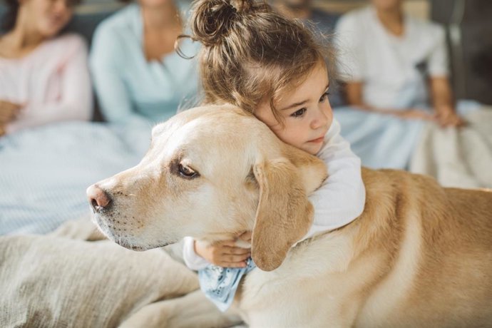 Archivo - Niña abrazando a un perro.