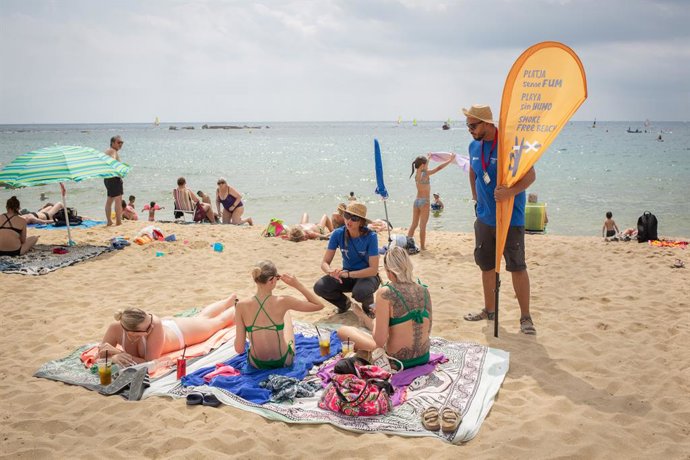 Archivo - Dos informadores conversan de la nueva prohibición de fumar con bañistas, en la playa del Bogatell, a 25 de julio de 2022, en Barcelona, Catalunya (España). El pleno del Ayuntamiento de Barcelona ha aprobado definitivamente la prohibición de fum