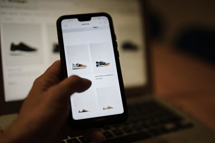 Archivo - Una persona observa en su móvil artículos de moda 