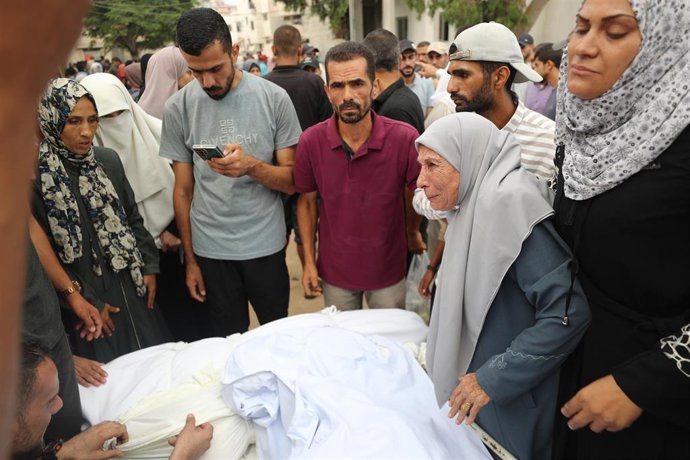 Varias personas junto a palestinos fallecidos en los últimos bombardeos en Gaza