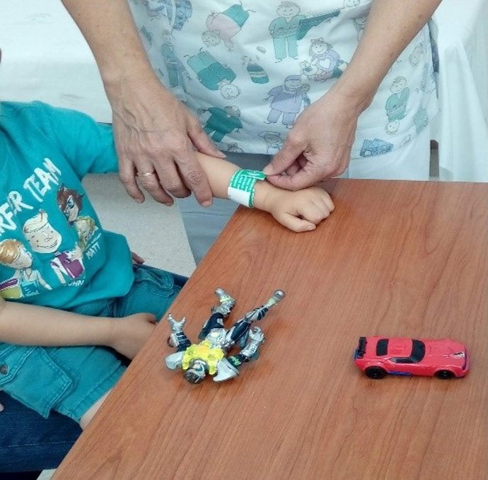 Archivo - Una enfermera coloca la pulsera indentificativa a un menor.