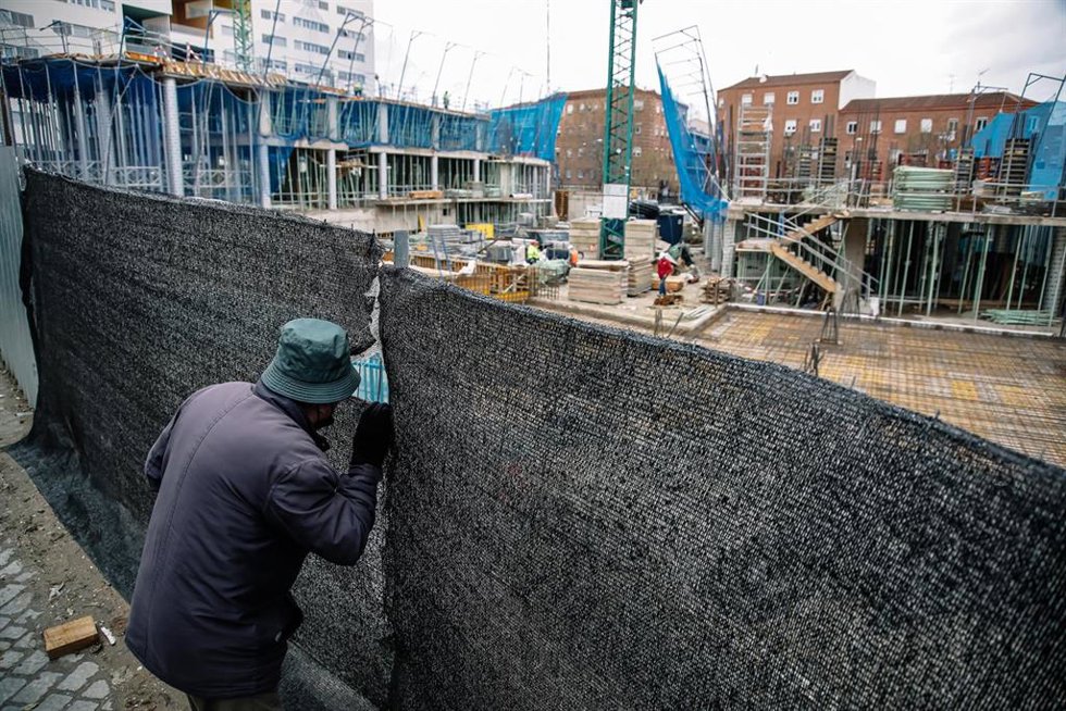 Archivo - Un hombre mira por el agujero de una lona de una obra en Vallecas