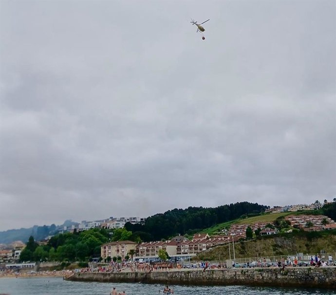 Imagen del helicóptero acudiendo al incendio en Luanco. Foto tomada desde la playa.
