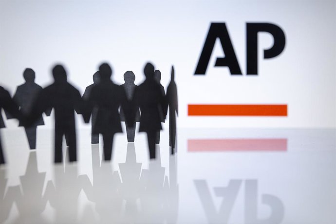 Archivo - November 18, 2024, Asuncion, Paraguay: The Associated Press (AP) logo is displayed behind cut out paper figures chain. The Associated Press said Monday that it would begin offering buyouts and lay off selected employees, part of a plan to reduce