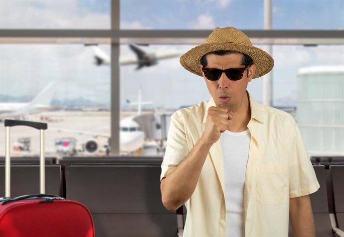 Archivo - Hombre de vacaciones tosiendo en el aeropuerto.