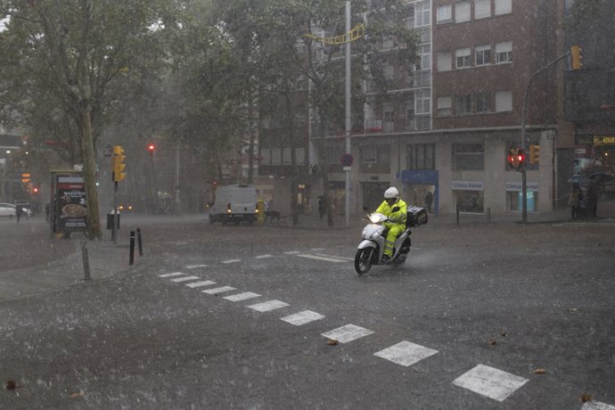 Archivo - Un repartidor amb moto durant una tempesta