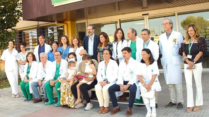 Lucía y su hermana (centro), en brazos de sus padres, junto a profesionales del Reina Sofía que han intervenido en el primer trasplante cardíaco infantil de donante en asistolia en Andalucía.