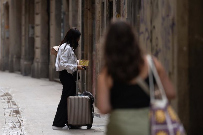 Archivo - Dos turistes amb les maletes a Barcelona