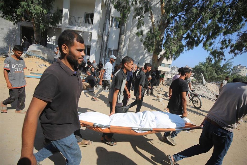 Palestinos trasladan un cadáver tras un bombardeo de Israel contra un edificio usado como refugio en la ciudad de Gaza, en el norte de la Franja de Gaza