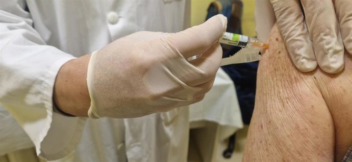 Archivo - Un profesional sanitario administra una dosis de vacuna a un paciente.