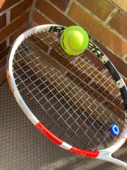 Archivo - Una raqueta de tenis con una pelota.