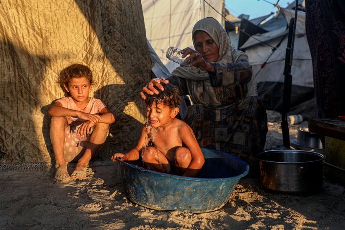 GAZA, 24 de julho de 2025 -- Uma criança palestina toma banho em meio ao calor do verão entre as tendas para pessoas deslocadas na costa da Cidade de Gaza, em 18 de julho de 2025. O Oriente Médio está enfrentando uma onda de calor escaldante nestas semana
