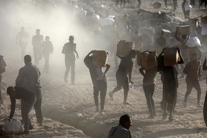 Archivo - 16 June 2025, Palestinian Territories, Gaza City: Palestinians carry food parcel, distributed by 'Gaza Humanitarian Relief Foundation' as people struggle with hunger amid the ongoing Israeli attacks on Gaza City. Photo: Omar Ashtawy/APA Images v