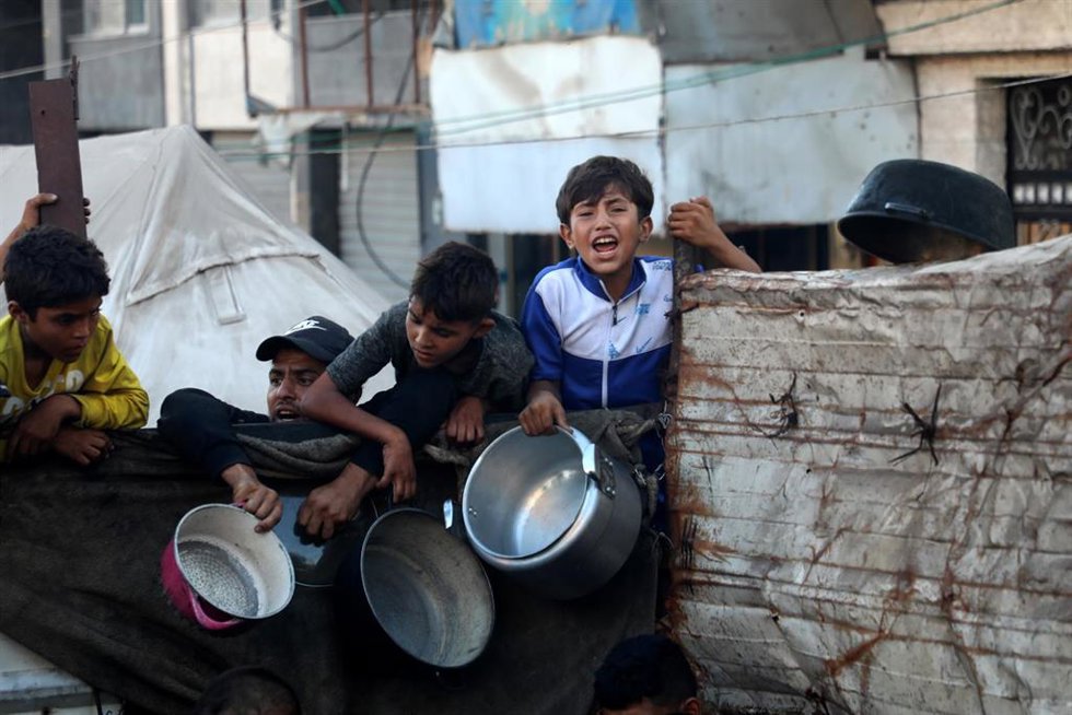 Adultos y menores aguardan a recibir alimentos en el barrio de Al Rimal, en el centro de la ciudad de Gaza