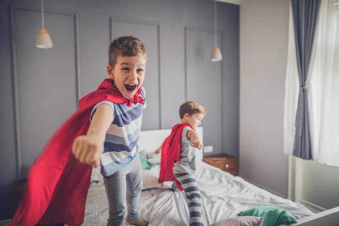 Archivo - Niños disfrazados de superhéroes jugando en la cama.