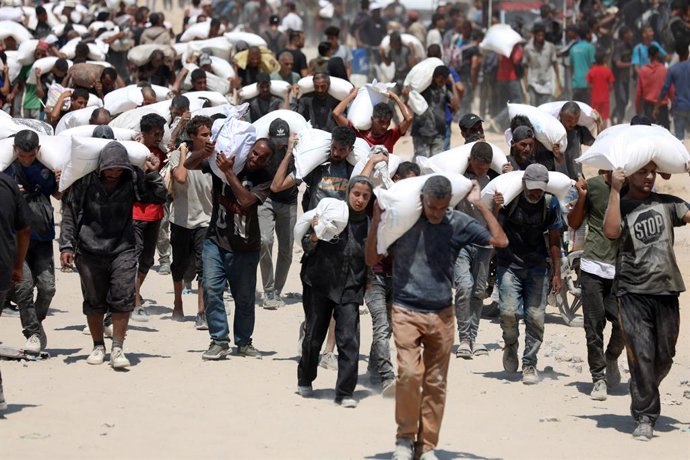 BEIT LAHIA, July 28, 2025  -- Palestinians carry bags of flour after the humanitarian aid entered Gaza through a border crossing, in Beit Lahia, northern Gaza Strip, on July 27, 2025.   The Israeli military on Sunday announced a daily 10-hour humanitarian