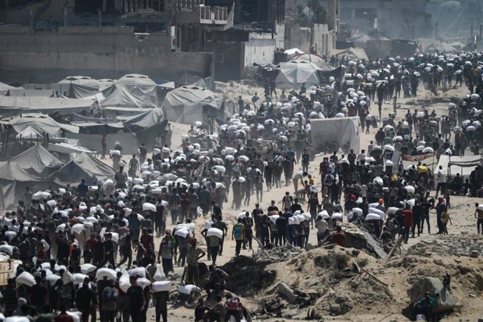 Palestinos cargados con harina tras la llegada de un convoy humanitario en ciudad de Gaza