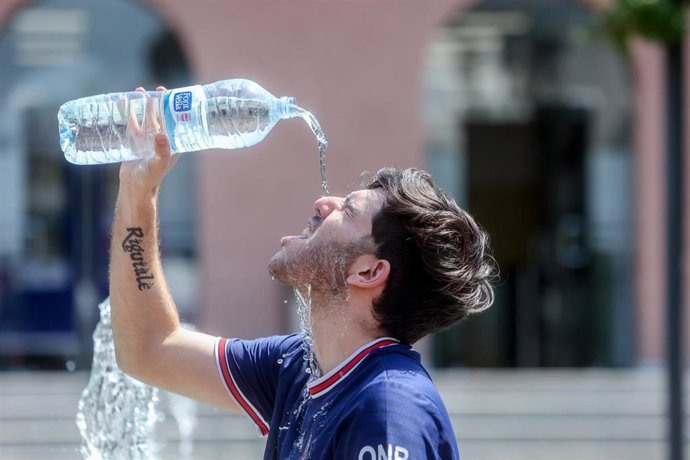 Archivo - Imagen de archivo de un joven que se tira una botella de agua por encima para combatir el calor.