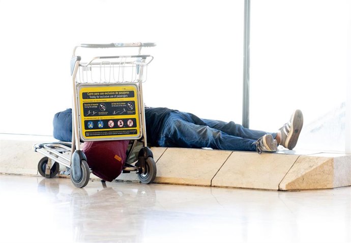Una persona tumbada en la Terminal 4 del aeropuerto Adolfo Suárez Madrid-Barajas, a 24 de julio de 2025, en Madrid (España). AENA prohíbe dormir o pernoctar en todas las terminales del aeropuerto a partir de hoy. La medida afecta principalmente a personas
