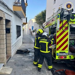 Efectivos de bomberos en la calle San Juan de Dios de Conil donde se ha incendiado una vivienda.