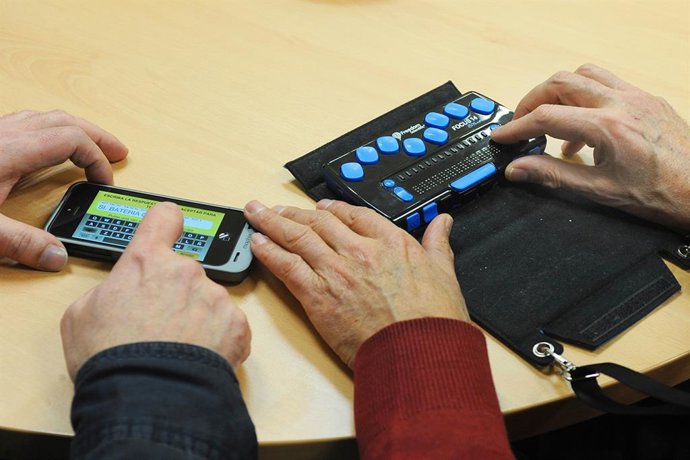 Archivo - Personas discapacitadas sordociegas comunicándose con un comunicador táctil