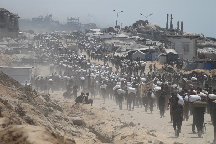 July 27, 2025, Gaza City, Gaza Strip, Palestinian Territory: People make their way along al-Rashid street in western Jabalia towards trucks carrying humanitarian aid after they entered the northern Gaza Strip through the Israeli-controlled Zikim border cr