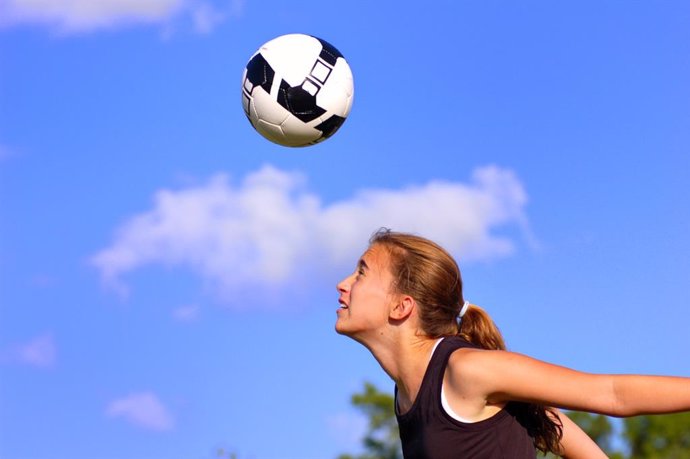 Archivo - Niña rematando de cabeza un balón de fútbol.