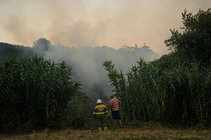 Dúas persoas observan o lume, a 29 de xullo de 2025, en Arbo, Pontevedra, Galicia.